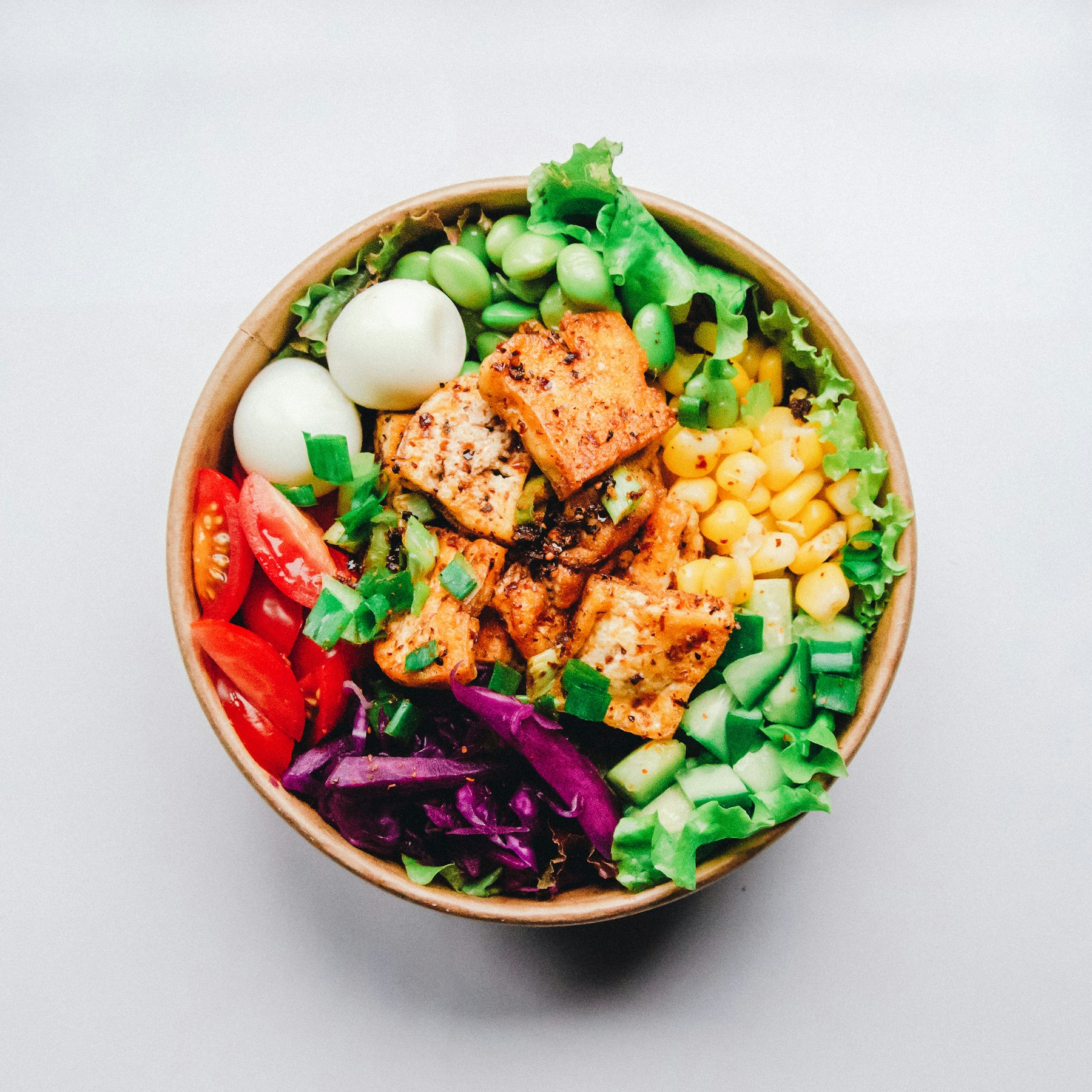 Bowl fresco servido en una caja para llevar: tofu, choclo, tomates y verdes